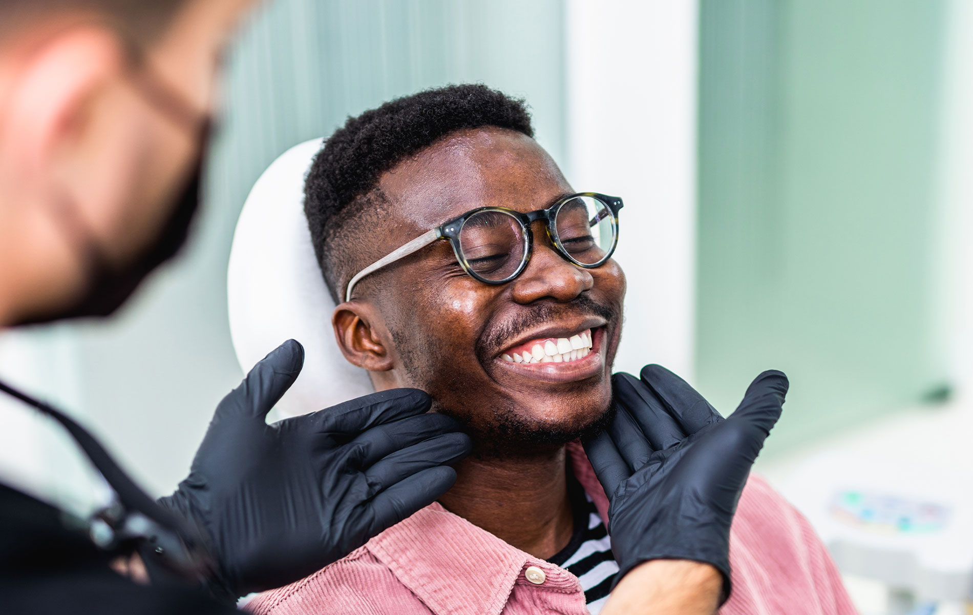 A man in a dental chair receiving dental care, smiling and looking upwards.