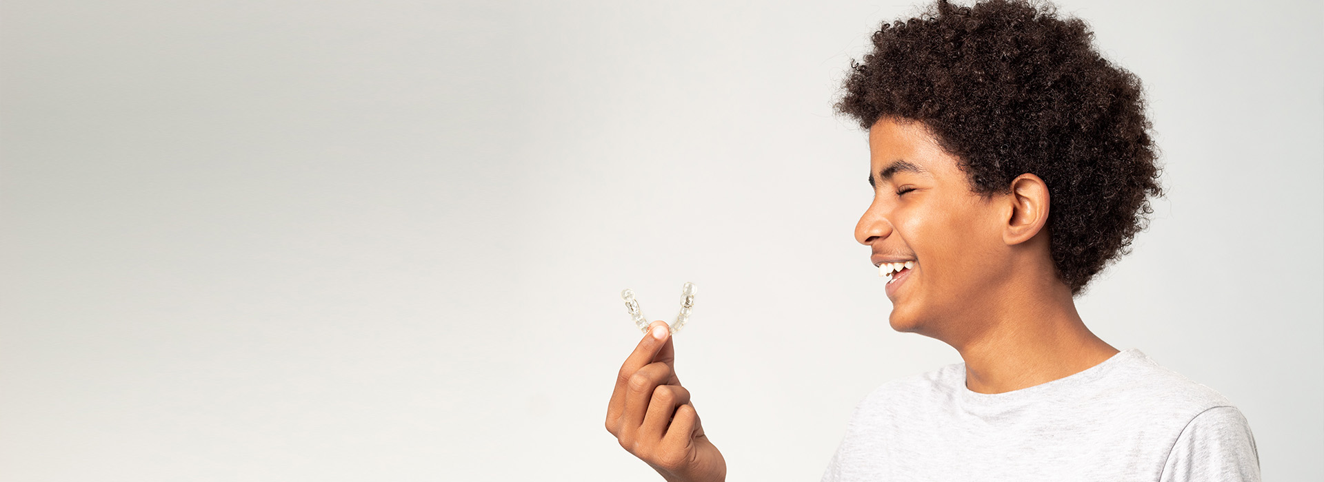 A person holding a flower with a joyful expression, set against a blurred background.