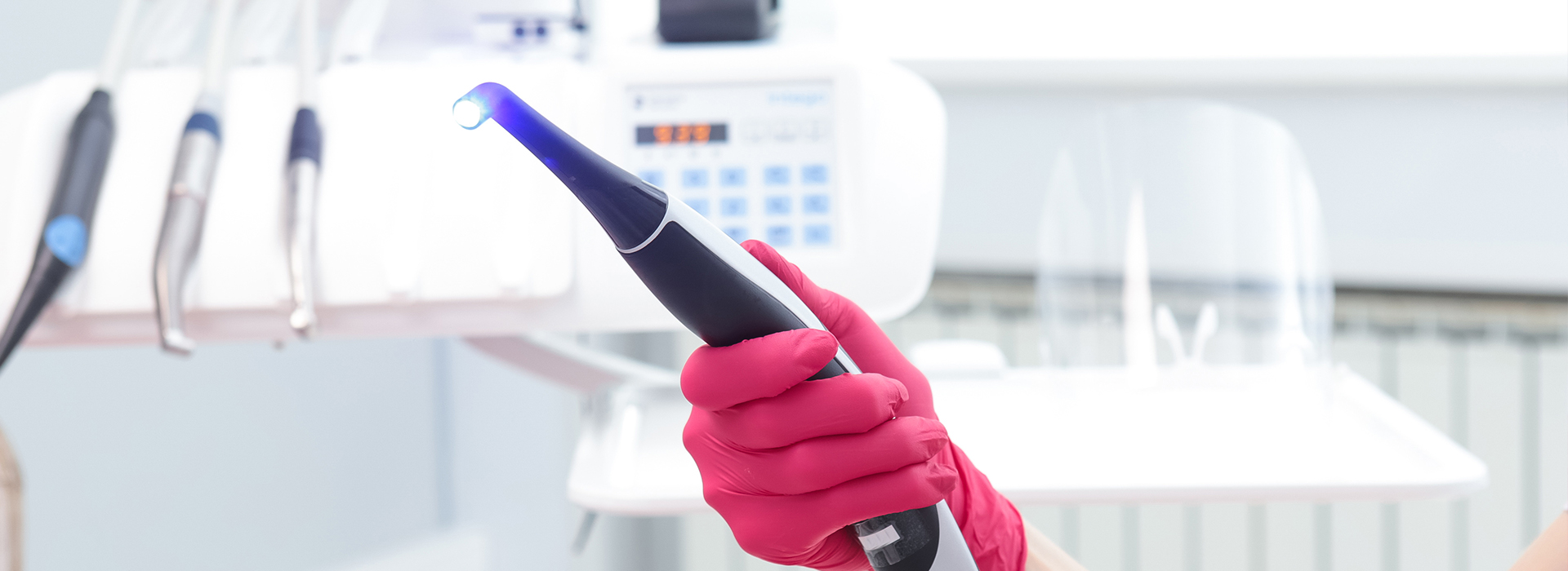 Woman holding a blue laser device, possibly in a medical or dental setting.