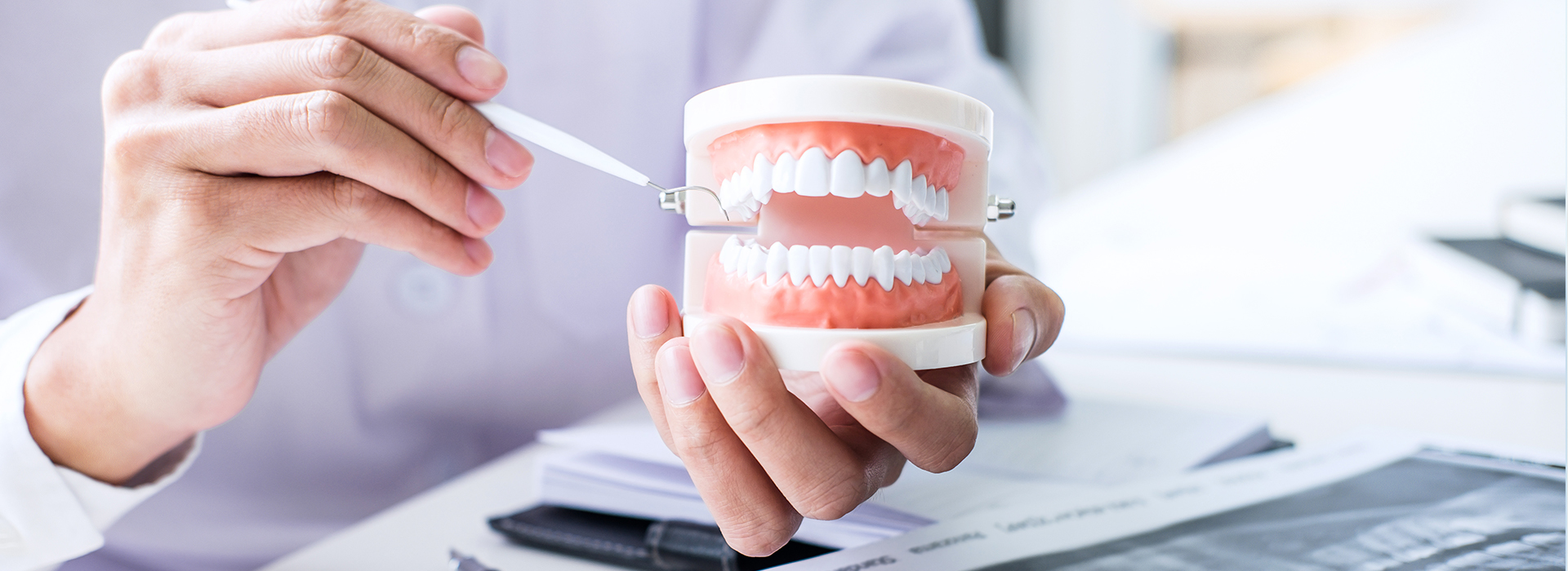 A person holding a toothbrush with their left hand while sitting at a desk.