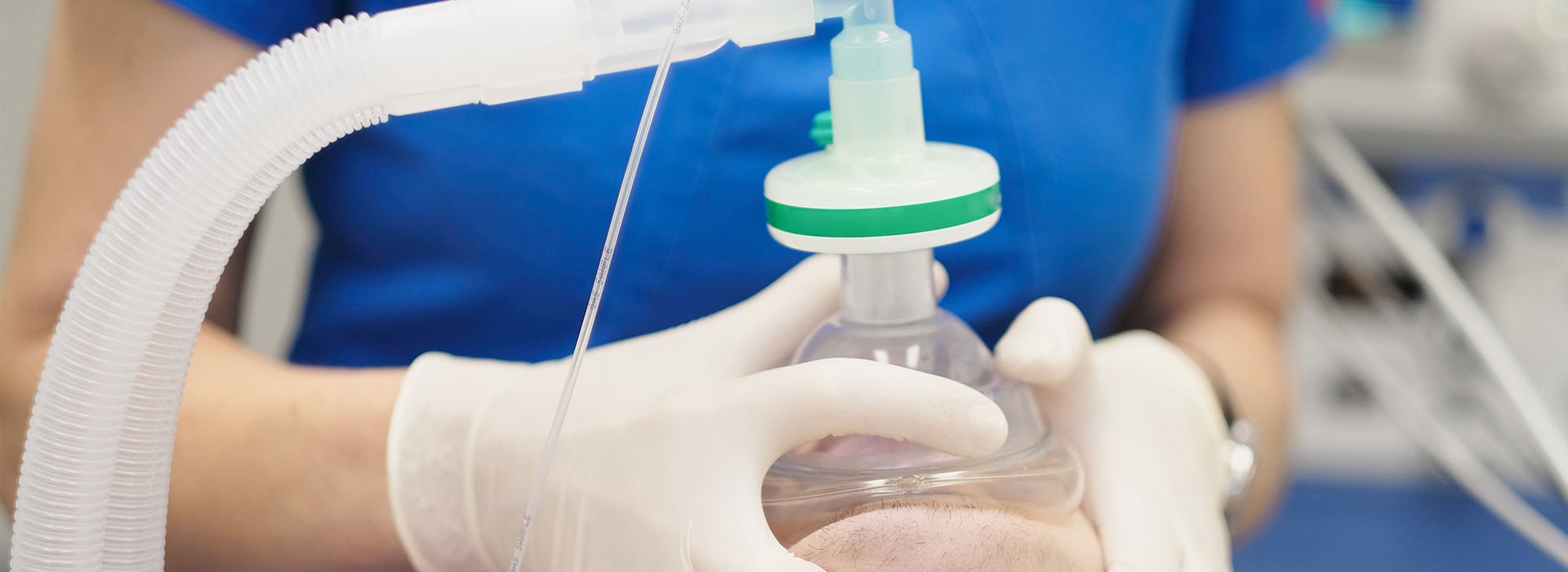 The image shows a person in a white lab coat holding a piece of medical equipment, which appears to be a nebulizer or similar device used for administering medication through the air.