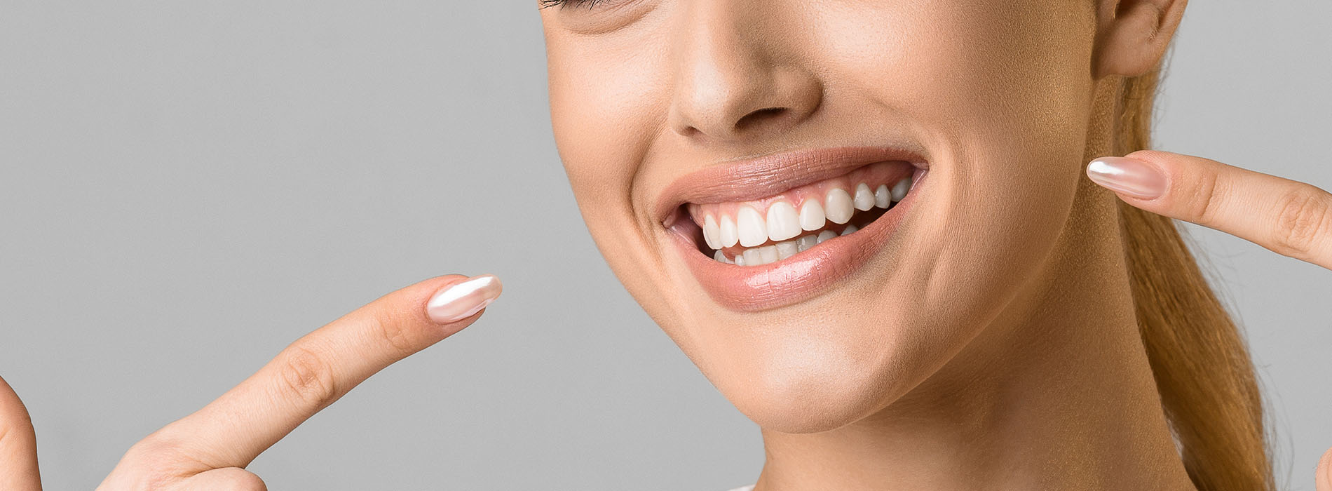 The image shows a smiling woman with her eyes closed, holding up two fingers near her face.