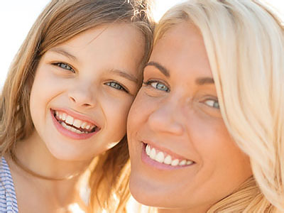 The image shows a woman and a young girl smiling at the camera, with the woman appearing to be the mother of the child.