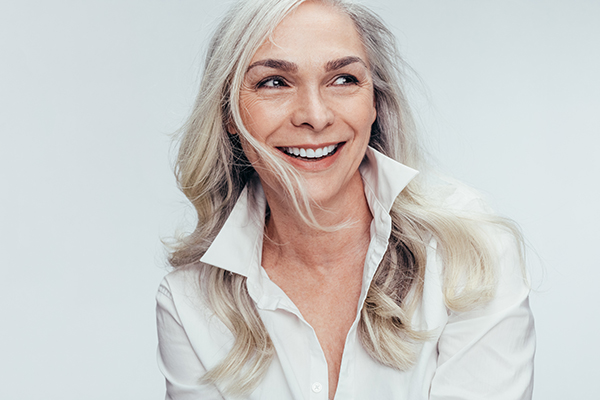 A woman with blonde hair, wearing a white shirt and smiling at the camera.