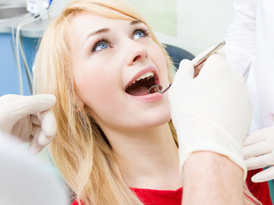 A woman receiving dental care, with a dentist performing an examination or procedure.