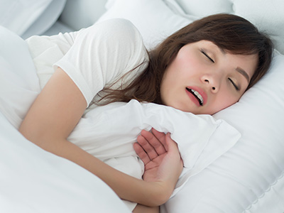 Woman lying in bed, eyes closed, with a white comforter.