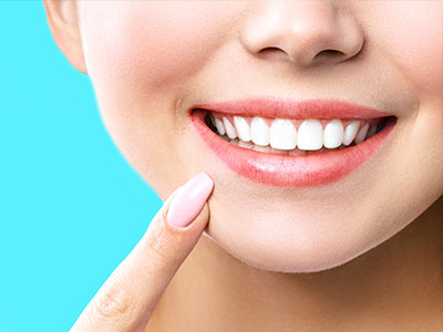 Image  A close-up of a person s face with a bright smile, focusing on teeth and lips against a blue background.